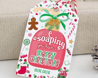Op de afbeelding: Een rood en groen kerstcadeau-etiket met een cartoon zeepstaaf en de tekst "esoaping you have a Merry Christmas" en "From, Callie".