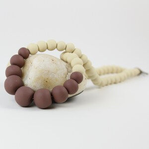 May include: A brown and beige silicone bead necklace with a rock in the center.
