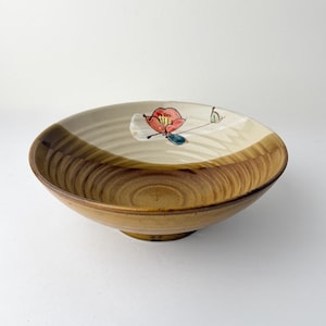 May include: A round ceramic bowl with a floral design. The bowl has a light brown exterior and a cream-colored interior with a red and white flower design. The bowl is approximately 3 inches tall and 8 inches in diameter.