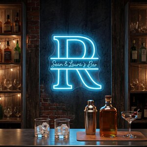 以下が含まれることがあります： 中央に「Sean & Laura's Bar」というテキストが水平に配置された、大きな文字「R」の明るい青色のネオンサイン。このサインは、グラスやボトルが置かれたバーカウンターの上の、暗い質感のある壁に取り付けられています。
