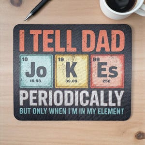 May include: A black rectangular mousepad with the text "I TELL DAD" in orange letters. Below, the words "Jo", "K", and "Es" are displayed as elements from the periodic table. The text "PERIODICALLY" and "BUT ONLY WHEN I'M IN MY ELEMENT" are also present.