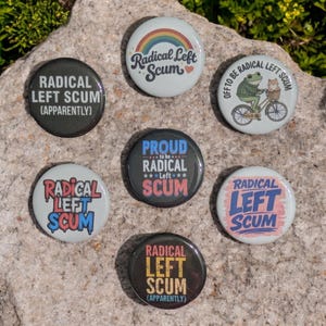 Op de afbeelding: Een verzameling van zeven ronde buttons met verschillende ontwerpen en tekst. De buttons bevatten zinnen als "Radical Left Scum" en "Proud to be Radical Left Scum". Sommige buttons hebben regenboog-, kikker- en kattenillustraties.