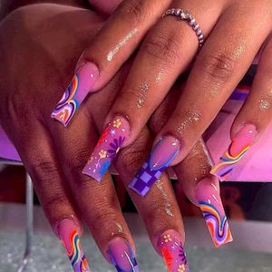 May include: Long, square-shaped acrylic nails with a variety of designs. The nails feature rainbow swirls, floral patterns, and a purple checkerboard design. The nails are painted in shades of pink, purple, and blue.