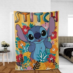 May include: A yellow throw blanket featuring the character Stitch from Lilo & Stitch. The blanket has a colorful design with Stitch surrounded by tropical flowers and foliage. The word "STITCH" is written across the top in a playful font.