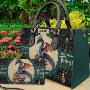 May include: A green tote bag and matching wallet set. The bag and wallet feature a dragon illustration with the text "That's what I do, I read books, and I know things." The bag has black handles and the name "Alexis".