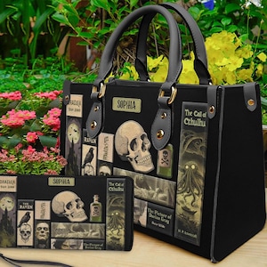 May include: Black handbag and matching wallet featuring a gothic theme. The bag and wallet have a skull, raven, and book cover designs. The bag has a top handle and gold-colored hardware. The wallet has a wrist strap and the name "Sophia".
