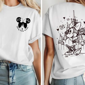 May include: White t-shirt featuring a black Minnie Mouse design on the back with a castle and fireworks. The front has a Minnie Mouse bow with the numbers 20 and 26, and the words "Disney Family Vacation".