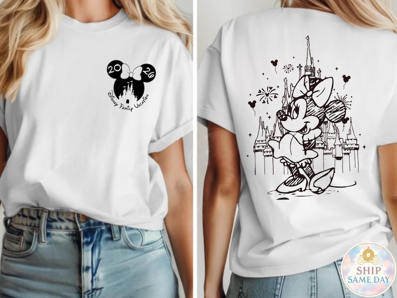 May include: White t-shirt featuring a black Minnie Mouse design on the back with a castle and fireworks. The front has a Minnie Mouse bow with the numbers 20 and 26, and the words "Disney Family Vacation".
