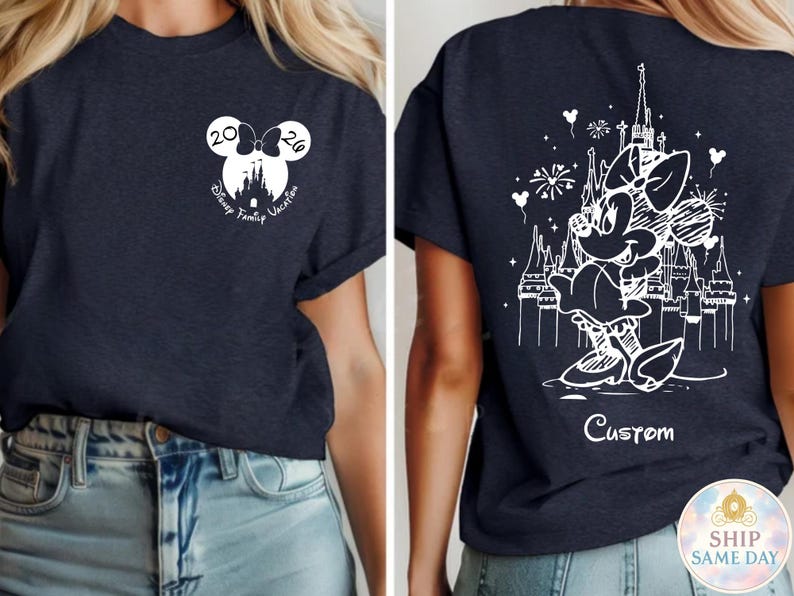 May include: Navy blue t-shirt featuring a white Minnie Mouse design on the back with a castle and fireworks. The front has a Mickey Mouse head with the text "Disney Family Vacation 2026".