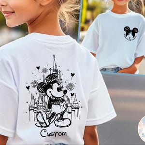 May include: White t-shirt featuring a black and white illustration of Mickey Mouse in front of a castle, with the word "Custom" below. A smaller image shows a similar shirt with a Mickey Mouse head and the text "Disney Family Vacation".