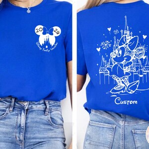 May include: Royal blue t-shirt featuring a white graphic of a Disney castle and Minnie Mouse. The front design includes the text "2026 Disney Family Vacation". The back design shows Minnie Mouse in front of the castle with the word "Custom".
