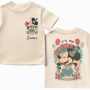 May include: Cream-colored t-shirt featuring a Mickey Mouse graphic with a birthday cake and the name "James". The back of the shirt says "It's my birthday" with Mickey holding a cake. Balloons and presents are also shown.
