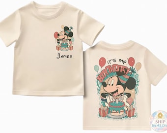 May include: Cream-colored t-shirt featuring a Mickey Mouse graphic with a birthday cake and the name "James". The back of the shirt says "It's my birthday" with Mickey holding a cake. Balloons and presents are also shown.