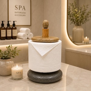 May include: A stylish toilet roll holder with a natural stone base and top. It has a wooden post and a stone finial. A roll of white toilet paper sits on the holder. The background includes a candle and a sign that says "SPA BATHROOM ACCESSORY."