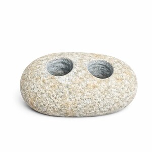 May include: A natural stone candle holder with two circular openings. The holder is oval-shaped and has a speckled, light gray and beige color. The openings are smooth and gray, designed to hold candles. The product is suitable for home decor.
