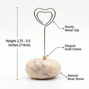 May include: A decorative photo holder with a sturdy metal heart-shaped clip. It features an elegant gold charm and a natural river stone base. The height is 2.75 to 3.5 inches.