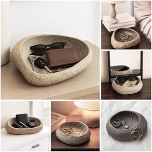 May include: A series of images featuring a stone-effect, oval-shaped tray. The tray is used to hold items such as sunglasses, wallets, keys, and jewellery. The neutral colour of the tray complements the items, creating a stylish storage solution.