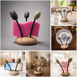 May include: A unique, handcrafted stone holder with three curved black metal stems topped with oval-shaped stones. The holder is designed to display a sponge, a phone, a plate, glasses, or a photo. The base is a smooth, rounded stone.