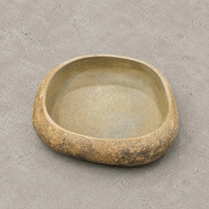 May include: A low, wide, rounded ceramic bowl with an irregular, organic shape. The exterior features a textured, mottled finish in shades of earthy brown and tan, while the interior has a smoother, lighter beige surface with visible brush strokes.