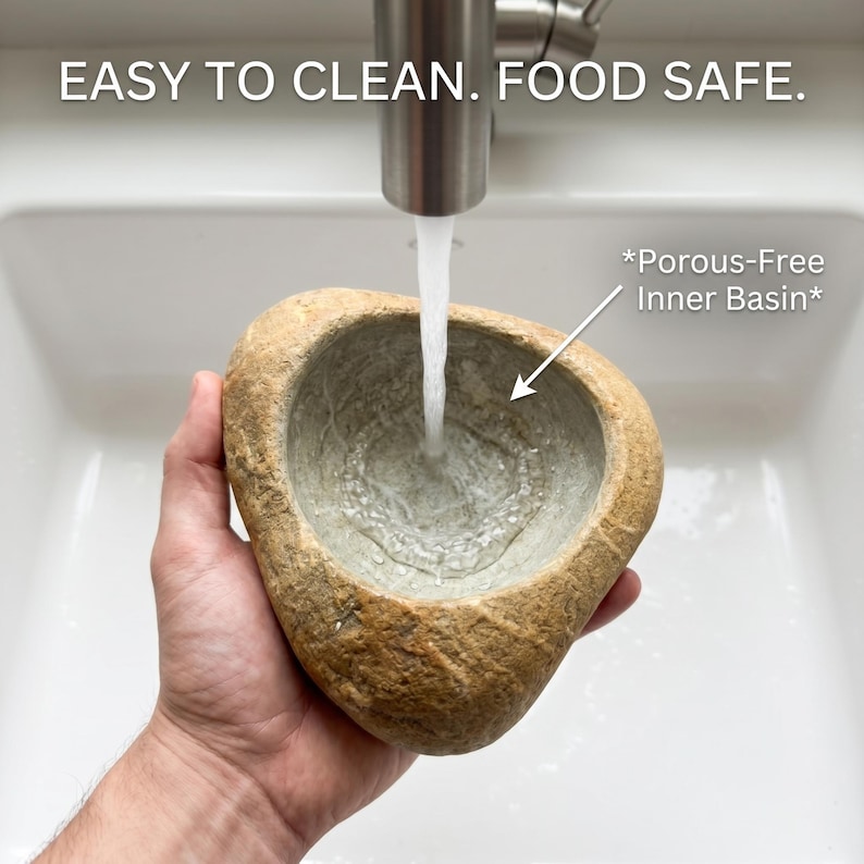 May include: A natural-looking, stone-like bowl is held under a stream of water from a stainless steel faucet. The bowl has a porous-free inner basin and is labeled "EASY TO CLEAN. FOOD SAFE."