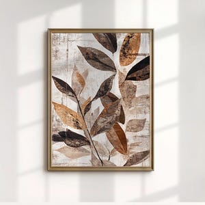 May include: A framed botanical art print featuring a close-up of stylized leaves in shades of brown, beige, and black. The leaves are arranged against a textured, off-white background, creating a natural and elegant aesthetic. The frame is a warm gold color.
