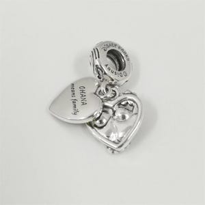 May include: A set of three ceramic mugs with a speckled, cream-colored glaze. Each mug features a different hand-painted design: a blue and green leaf, a yellow flower, and a red berry. The mugs have a simple, rounded shape.