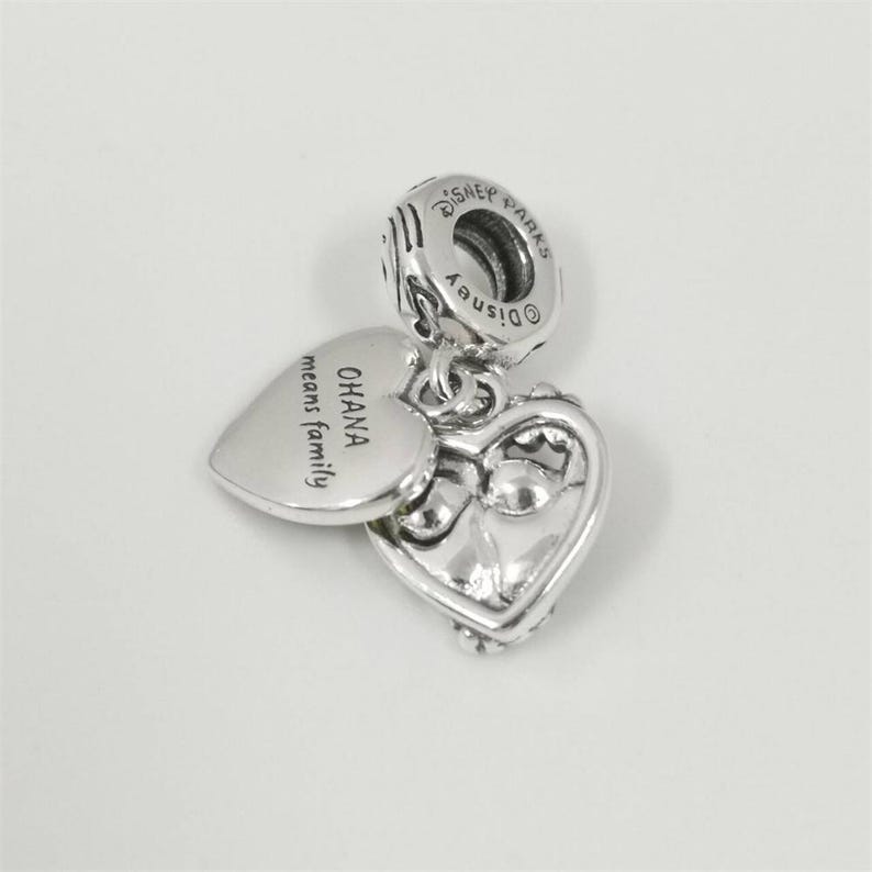 May include: A set of three ceramic mugs with a speckled, cream-colored glaze. Each mug features a different hand-painted design: a blue and green leaf, a yellow flower, and a red berry. The mugs have a simple, rounded shape.