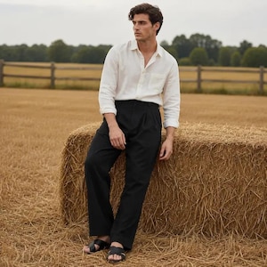 May include: A long-sleeved white button-down shirt with a chest pocket, paired with black trousers featuring a pleated waist and straight-leg cut, and black leather slide sandals with wide crisscross straps across the top of the feet.