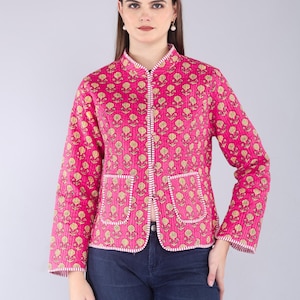 May include: A pink quilted jacket with a floral pattern in yellow and white. The jacket has a mandarin collar, long sleeves, and two front pockets. The jacket is approximately 24 inches long.