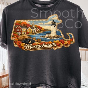 Puede incluir: Camiseta gris oscuro con un diseño bordado del contorno del estado de Massachusetts. El diseño incluye un faro, casas y el texto "Massachusetts". El diseño está rodeado de hojas de otoño.