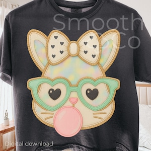 May include: Dark gray t-shirt featuring a cartoon cat face with heart-shaped glasses and a bow. The cat is blowing a bubblegum bubble. The shirt has the text "Smooth Co" and "Digital download".