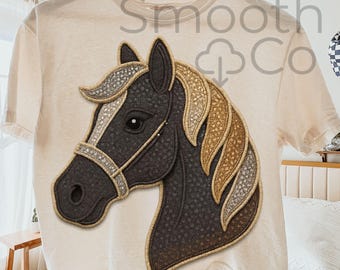 May include: Cream-colored t-shirt featuring a detailed horse head design. The horse has a dark gray face, a tan and silver mane, and a decorative bridle. The text "Smooth Co" is visible on the shirt.