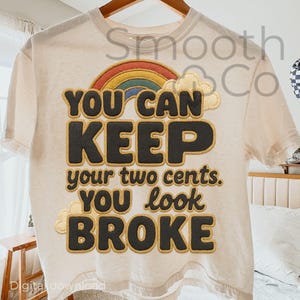 May include: Cream-colored t-shirt with a rainbow and text that reads "YOU CAN KEEP your two cents. YOU look BROKE." The design features a rainbow with yellow, orange, red, and blue colors. The text is in a bold, black font with a gold outline.