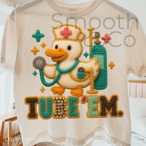 May include: Cream-colored t-shirt featuring a crocheted duck wearing a nurse's hat and stethoscope. The duck holds a stethoscope and stands next to a teal oxygen tank. The text "TUBE 'EM" is below the duck.