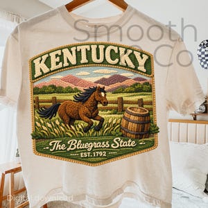 May include: Off-white t-shirt with a detailed graphic of a brown horse running in a field, a wooden barrel, and the text "KENTUCKY" above "The Bluegrass State". The design includes the text "EST. 1792".