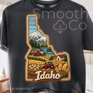 May include: Dark gray t-shirt featuring a detailed embroidered design of the state of Idaho. The design includes a landscape with mountains, a lake, farmland, a red tractor, and the word "Idaho". The shirt also has the text "Smooth Co" and "Digital download".