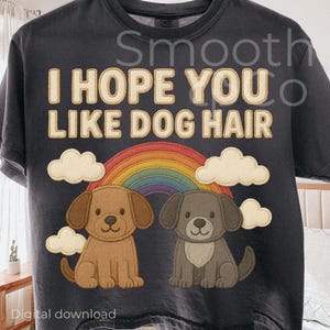 May include: Dark gray t-shirt with the text "I HOPE YOU LIKE DOG HAIR" above a rainbow and two cartoon puppies. The puppies are brown and gray, with white clouds on either side of the rainbow.