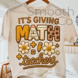 May include: Cream-coloured t-shirt with a colourful graphic design. The design features the text "IT'S GIVING MATH teacher" in a playful, textured font, along with math symbols and daisy graphics. A fun and educational apparel item.
