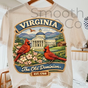 Może przedstawiać: Kremowa koszulka z szczegółowym haftowanym wzorem symboli stanu Wirginii. Projekt zawiera dwa czerwone kardynały, budynek Kapitolu stanu oraz napisy "VIRGINIA" i "The Old Dominion EST. 1788".