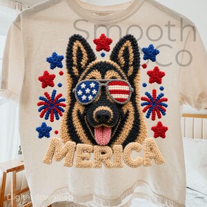 Puede incluir: Una camiseta de color crema con un gráfico de un pastor alemán que lleva gafas de sol con patrones de la bandera estadounidense. El diseño incluye estrellas y fuegos artificiales rojos y azules, con el texto MERICA en letras beige.