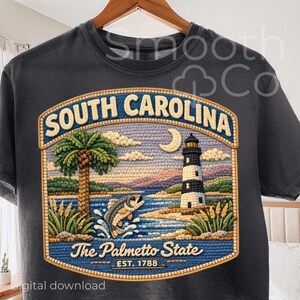 May include: Dark gray t-shirt featuring a detailed embroidered design of South Carolina. The design includes a palm tree, lighthouse, jumping fish, and the text "South Carolina" and "The Palmetto State".