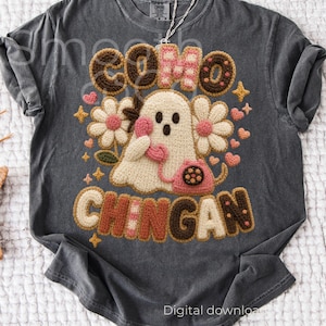 Könnte beinhalten: Dunkelgraues T-Shirt mit einem Häkeldesign, das einen Geist mit einem rosa Telefon zeigt, umgeben von Blumen, Herzen und Sternen. Der Text "COMO CHINGAN" ist oberhalb und unterhalb des Geistes zu sehen. Die Worte "Digital download" stehen unten.