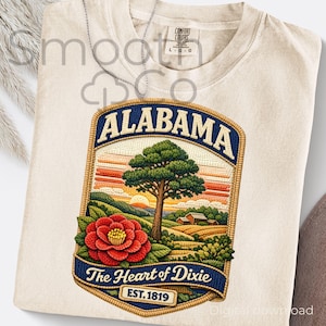 May include: Cream-colored t-shirt with a detailed graphic of an Alabama landscape. The design features a tree, sunset, and a red flower, with the text "ALABAMA" and "The Heart of Dixie" on a patch. The shirt has a Comfort Colors tag.