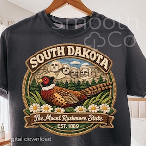 May include: Dark grey t-shirt with an embroidered design. The design features Mount Rushmore, a pheasant, and the text "South Dakota" and "The Mount Rushmore State - EST. 1889".