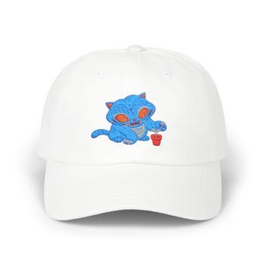 May include: White baseball cap featuring an embroidered blue cat with orange eyes and a small red pot. The cat is holding the pot with a small plant. The cap has a curved brim and a rounded crown.