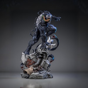 Może przedstawiać: Szczegółowa statua postaci Venom z komiksów Marvela. Postać jest głównie czarna z białymi akcentami, białym symbolem pająka i groźnymi otwartymi ustami. Statua stoi na szczegółowej podstawie z elementami architektonicznymi.