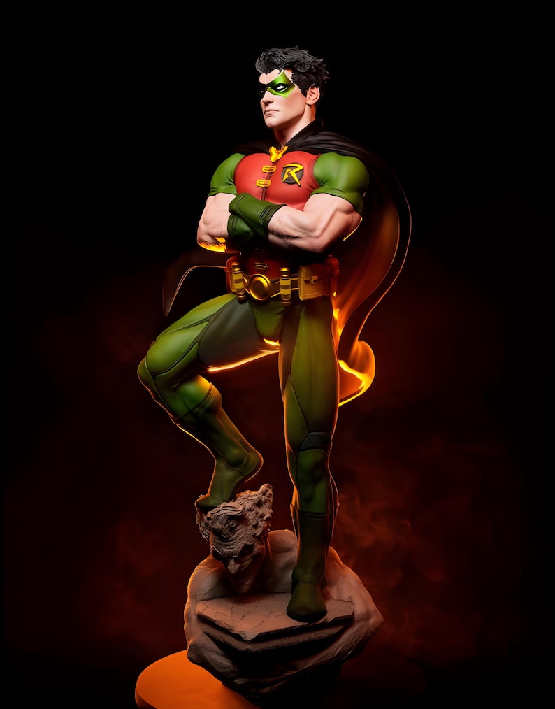 May include: A detailed statue of Robin, a DC Comics superhero, in a dynamic pose. The figure wears a green and red costume with a black cape, green mask, and a gold belt. The statue is standing on a stone base with a sculpted face.