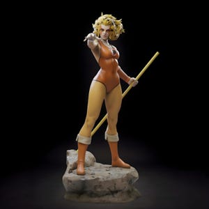 May include: A detailed statue of a female character in an orange bodysuit, boots, and gloves, holding a yellow staff. The figure stands on a rocky base, with a determined expression and outstretched arm. The background is black.