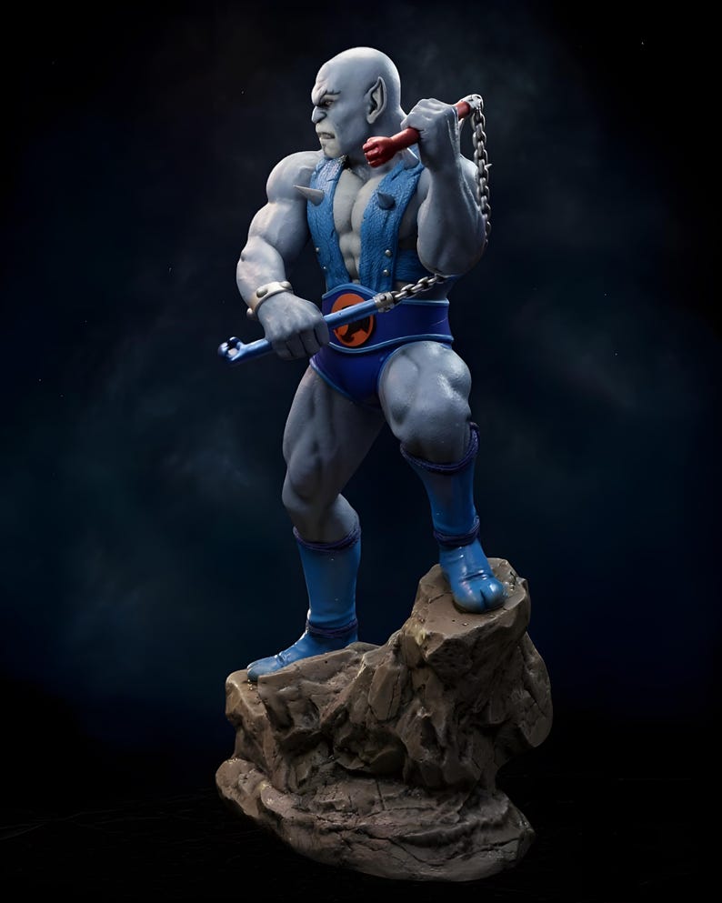 Puede incluir: Figura detallada de un personaje humanoide musculoso de piel gris, posando sobre una base rocosa. La figura viste un atuendo azul con un cintur&oacute;n con un emblema naranja. Sostiene un arma de cadena con detalles rojos y azules.