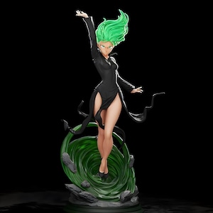 May include: A detailed figurine of a character with green hair and a black dress. The figure is posed dynamically, with one arm raised. A green, swirling energy effect forms a base, with dark rocks around it. The background is black.